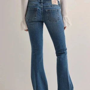 True Religion blå bootcut jeans - Snygga blå jeans från True Religion med bootcut-snitt och klassisk femficksdesign. Jeansen har ikoniska broderade bakfickor och låg midja. Säljer då de va förstora på mig. Men helt nya prislapp sitter kvar.