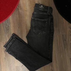 Svarta Replay jeans straight fit - Säljer ett par svarta jeans från Replay med klassisk femficksdesign och raka ben. Jeansen har diskreta slitningar och snygga detaljer på bakfickorna. Passar dig som är runt 160. 