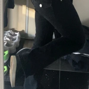 Svarta bootcut jeans med fickdetaljer - Säljer ett par svarta bootcut jeans med snygga fickor bak som har lock och silvriga knappar. Från Gina Tricot, deras yk8 jeans. Mycket bra skick.