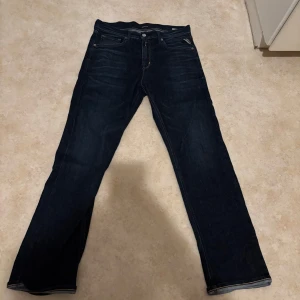 Mörkblå Replay jeans straight fit - Säljer ett par mörkblå jeans från Replay i klassisk straight fit. Jeansen har fem fickor, snygga kontrastsömmar och är tillverkade i slitstarkt bomullstyg. Perfekta för dig som gillar en tidlös och clean look.