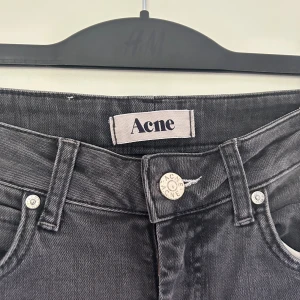 Grå jeans från Acne Studios - Säljer ett par svarta skinny jeans från Acne Studios med klassisk femficksdesign och snyggt slitna detaljer. Jeansen har en smal passform och är tillverkade i stretchig denim för en bekväm känsla. Perfekta till sneakers eller boots. Enda att anmärka på är ett ena hylsan gått av, därav priset. Storlek 27/32. 