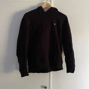 Svart hoodie från Polo Ralph Lauren - Svart hoodie från Polo Ralph Lauren med klassisk broderad logga på bröstet. Tröjan har huva, känguruficka och är tillverkad i mjuk bomull. Skriv vid intresse!