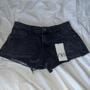 Svarta lågmidjade jeansshorts Zara - Snygga svarta jeansshorts från Zara med låg midja och råa, slitna detaljer. Fick i födelsedagspresent men säljer då de inte passade💓