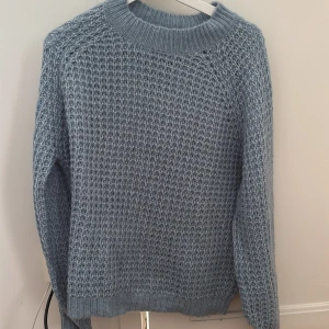 Ljusblå stickad tröja från lager 157 - Säljer en blå stickad tröja från lager 157 i storlek M. Tröjan har ett grovt, strukturerat stickmönster och ribbade muddar vid hals, ärmslut och nederkant. Även denna är knappt använd. 