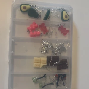 Roliga örhängen med matmotiv - Säljer ett gäng unika örhängen med olika matmotiv som avokado, geléhallon, mjölkchoklad och läskflaskor. Färgerna är blandade med inslag av grönt, rosa, gult och brunt. Perfekt för dig som vill ha något annorlunda och lekfullt i öronen!