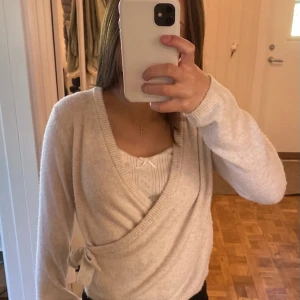 Beige omlottkofta från Kappahl - Supermysig beige omlottkofta från Kappahl med knyt i sidan och ribbade kanter. Koftan har lång ärm och är i ett mjukt, stickat material som passar perfekt till lager-på-lager. Enkel att styla med både jeans och kjol!❤️💕💕