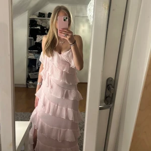 Ljusrosa klänning med volanger - Superfin ljusrosa långklänning som kommer ifrån Vila. Klänningen är i nyskick och är använd 1 gång 