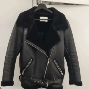 Svart teddyjacka från Zara Woman - Snygg svart teddyjacka från Zara Woman med bred krage, dragkedja i sned modell och bälte i midjan. Jackan har två dragkedjefickor framtill och mjukt foder. Perfekt för kalla dagar och ger en cool vibe till din outfit.