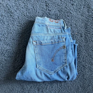 Dondup jeans - Säljer ett par ljusblå jeans från dondup i storlek 32. Jeansen har ett stort hål på ena låret,  råa kanter nertill och klassiska bakfickor med Replay-detaljer. Perfekt för dig som gillar en avslappnad och edgy stil. Jeansen är SYNLIGT uppsydda så utgå från måtten längd 89cm och midja 37cm. Jag tar ej emot returer pga storleken. KAN INTE SKICKA BILD NÄR JAG BÄR JEANSEN SÅ JAG EK KAN HA DENNA STORLEK :)priset på 199kr är inte förhandlingsbart:(
