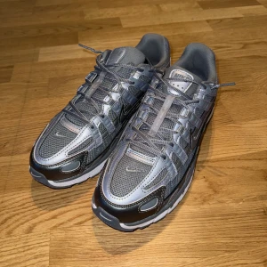Nike P-6000 sneakers i silver och grå - Nike P-6000 - en av de mest eftertraktade sneakers just nu! Retro-look med modern komfort, perfekt till både streetwear och vardagsfit. Knappt använda och i riktigt fräscht skick, sulor och material är i toppform. Den här färgkombon säljer ofta slut snabbt, så det här är din chans att få ett par utan att betala nypris.