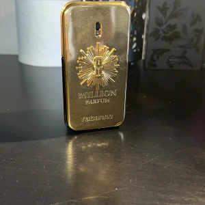 Paco Rabanne 1 Million Parfum 50ml - Exklusiv parfymflaska i guldmetall och svart från Paco Rabanne, 1 Million Parfum. Flaskan har en unik rektangulär form med präglad solsymbol och logotyp på framsidan. Rymmer 50 ml och har en lyxig, glänsande finish som verkligen sticker ut i badrumshyllan.