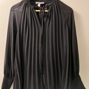 Svart plisserad blus från hm - Super snygg och classy blus från hm. Köpte för några år sen för nyår men inte använd så mycket efter det. Är xs men stor i storleken så passa upp till M 