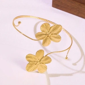 Guldfärgat armband med blommor - Unikt armband i guldfärg med två stora blommor som detaljer. Armbandet är öppet och böjbart, vilket gör det lätt att anpassa runt överarmen. Blommorna har en snygg, räfflad yta som ger extra glans och karaktär. Den har inte kommit till användning någon gång då jag inte hittat något att matcha den med. 