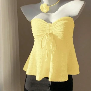 Gul bandeau tubtopp med knyt - Superfin ljusgul bandeau tubtopp med volangig nederdel och snygg knytning framtill. Helt oanvänd!