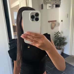 Svart croppad topp med volangärmar - Säljer en svart croppad topp från Bershka med snygga volangärmar. Toppen är ribbad och har en tight passform som framhäver figuren. Perfekt för dig som gillar trendiga detaljer och vill sticka ut lite extra.