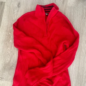 Röd ribbad tröja Polo Jeans Co. - Riktigt snygg röd ribbstickad tröja från Polo Jeans Co. med halv dragkedja och ståkrage. Insidan av kragen har coola marinblå ränder. Tillverkad i 100% bomull och har långa ärmar. Perfekt för dig som gillar klassisk men ändå sportig stil.
