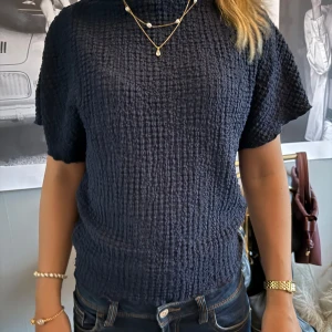 Mörkblå kortärmad tröja - Säljer en mörkblå tröja med korta ärmar och hög hals. Tröjan har en grov, strukturerat material . Trendig tröja från Zara som inte går att hitta längre 