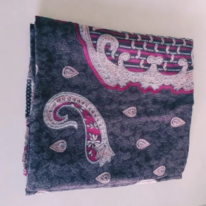 Mörkblå paisleymönstrad halsduk - Snygg och tunn halsduk i mörkblått med paisleyinspirerat mönster i vinrött och beige. Perfekt att slänga över axlarna för en cool och stilren look. Lätt material som känns skönt mot huden och ger outfiten en extra touch.  Helt skick dock noppror