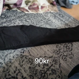 Svarta skinny jeans med ficka - Svarta jeans med tight passform och en stor ficka på benet. Snygga och enkla att matcha till det mesta. Perfekta för dig som gillar en stilren look med lite edge.