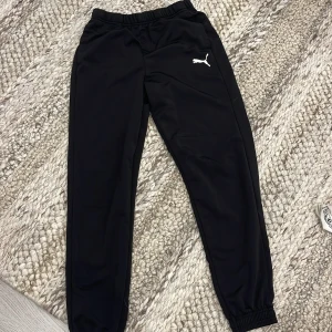 Svarta mjukisbyxor från Puma - Svarta mjukisbyxor från Puma med elastisk midja och snörning. 