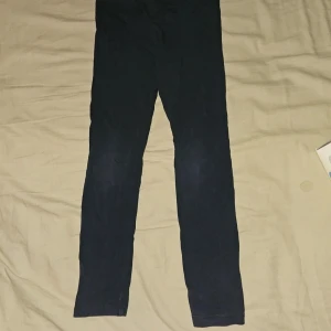 Svarta leggings från H&M, stl 122 - Svarta leggings från H&M i stretchigt material. De har en smal passform och är perfekta för en enkel och clean look. Midjan är elastisk för extra komfort. Passar dig som gillar basic och stilrena plagg. Lite ljusare över knäna