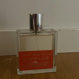 Vintage 1956 Eau de Cologne 100ml - Stilren parfymflaska i glas med silverfärgat lock. Doften är citrusig med fräscha inslag av bergamott, balanserad med amber och vit mysk. Flaskan rymmer 100 ml och har en modern, fyrkantig design med orange etikett. Den är använd max 10 gånger. Den har ingen förpackning me sig