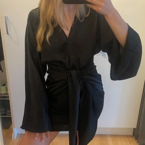 Svart fest klänning  - Supersnygg festlig klänning från Gina med vida ärmar (se bild) , endast använd en gång då den tyvärr är för stor för mig! Klänningen får att knyta som en rosett i fram men även på sidan. 