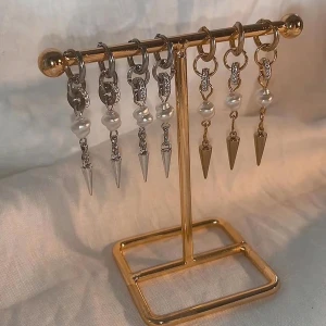 Örhängen med pärlor och spikes - Coola örhängen i både silver och guld med gnistrande detaljer, vita pärlor och spetsiga spikes som hänger ner. Perfekt accessoar för att lyfta din stil med en edgy touch och lite bling.