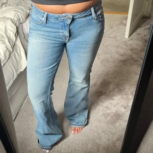 Ljusblå bootcut jeans Tommy hilfiger - Säljer ett par ljusblå bootcut jeans  med klassisk femficksmodell och snyggt sliten tvätt. Jeansen har normal passform, låg midja och ikonisk logga på bakfickan samt bakre linningen. Perfekta för en chill och trendig look.