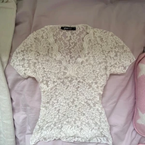 Vit spetsblus från Gina Tricot XS - Supersöt vit blus från Gina Tricot i storlek XS. Helt i spets med blommigt mönster och korta ärmar. 