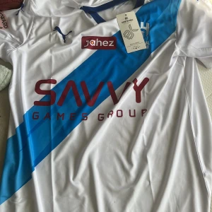 Al Hilal Neymar Jr #10 fotbollströja - Snygg Al Hilal fotbollströja med Neymar Jr och nummer 10 på ryggen. Tröjan är vit med ett blått diagonalt band över bröstet, blå detaljer och röda tryck. Tillverkad i lätt och ventilerande polyester, perfekt för match eller träning.