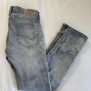 Jeans från Jack & Jones - Snygga ljusgrå jeans från Jack & Jones, modell Slim/Glenn. Jeansen har en slim passform och klassisk femficksdesign. Tillverkade i mjuk bomull med lite stretch för extra komfort. Perfekta till sneakers och t-shirt för en clean look.