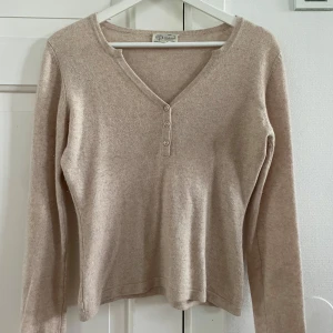 Beige/ljusrosa kashmirtröja med knappar  - Supermjuk beige/ljusrosa tröja i 100% kashmir från CF Cashmere. V-ringad med tre knappar framtill och långärmad modell🩷💛 Mer rosa irl än på bild