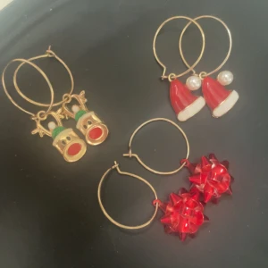 3-pack juliga örhängen med motiv - Tre par örhängen med julkänsla: ett par med röda rosett-bows, ett par med tomteluvor och pärldetalj, samt ett par med söta renar i guld, grönt och rött. Perfekta för att maxa julstämningen och sticka ut med roliga detaljer.