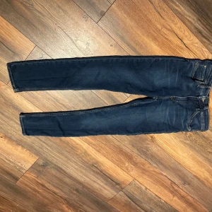 Mörkblå skinny jeans - Snygga mörkblå jeans med skinny fit och klassisk femficksdesign. Jeansen har guldfärgade sömmar och är tillverkade i stretchigt denimtyg för en bekväm passform. Perfekta för dig som gillar en smal siluett och stilren look.