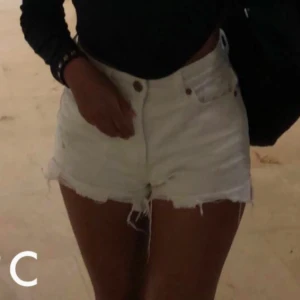 Vita jeansshorts från FB Sister XS - Snygga vita jeansshorts från FB Sister i storlek XS. De har hög midja, slitna detaljer och fransiga benslut för en cool och avslappnad look. Perfekta för varma dagar och festivaler. Klassisk femficksmodell med knapp och dragkedja.