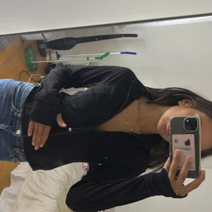 Svart tunn jacka från Amisu - Svart tunn gymjacka från New Yorker med dragkedja framtill och hög krage. Jackan är figurnära och har långa ärmar. Materialet är mjukt och stretchigt, perfekt för lager-på-lager. Perfekt ”tröja” för att ha med till gymmet eller liknande. Liten i storlek så skulle säga att en S passar denna tröjan