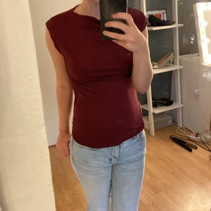 Vinröd ärmlös topp i bomull - Säljer en vinröd, tight och ärmlös topp med rund hals. Toppen är enkel och stilren, perfekt att matcha med jeans eller kjol. Gjord i mjuk bomull som sitter skönt mot kroppen. Passar dig som gillar minimalistisk och clean stil.