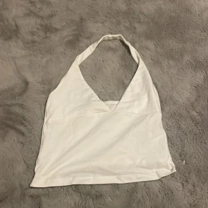 Vit halterneck linnetopp Subdued XS - Säljer en vit halterneck linnetopp från Subdued i storlek XS. Toppen har v-ringning och är ärmlös med en snygg omlottkänsla framtill. Perfekt för varma dagar och enkel att matcha med jeans eller kjol.