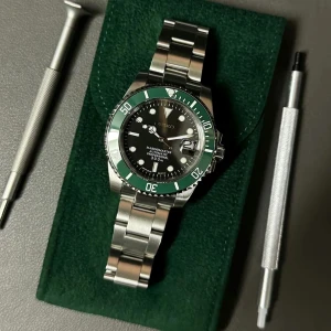 Seiko Marinemaster automatisk klocka - Snygg Seiko Marinemaster automatisk klocka med svart urtavla och grön vridring. Robust boett och länk i silverfärgat stål. Index och visare är tydliga och lysande, perfekt för dig som gillar stilren design och dykarkänsla. Vattentät till 300 meter.