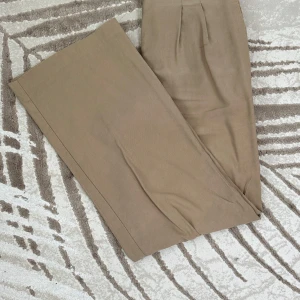 Beige vida linnebyxor  - Snygga linnebyxor med fickor i färgen beige från Pearl. Byxorna är i fint skick, dock förekommer det slitage (se bilder).   Storlek: 38 Material: 65% Viskos och 35% polyester