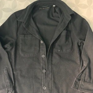 Overshirt från Donce de la sense St, XS - Stilren svart overshirt med två bröstfickor och knäppning framtill. Jackan har klassisk krage och långa ärmar med knappdetaljer vid ärmslut. Perfekt för lager-på-lager och enkel att matcha med olika outfits.