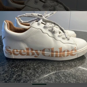 Vita sneakers från See By Chloé - Snygga vita sneakers från See By Chloé med bruna detaljer och stor logga på sidan. Skorna har rund tå, platt sula och snörning. 