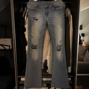 Ljusblå bootcut jeans med slitningar - Säljer ett par ljusblå jeans med bootcut passform och snygga slitningar framtill och på bakfickorna. Jeanden är låg midjade med storlek 38💗