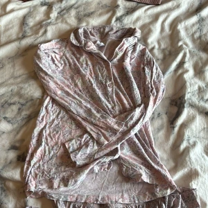 Blommig långärmad skjorta & pyjamas byxor från Kappahl - Supersöt långärmad skjorta & pyjamas byxor från Kappahl i storlek 146/152. Skjortan & byxorna har ett blommigt mönster i ljusa pastellfärger som rosa, lila och grönt. Mjuk och skön bomullskänsla, perfekt för dig som gillar avslappnad och söt stil.