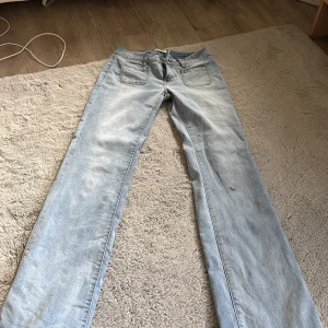 Ljusblå jeans från Madlady, straight fit - Säljer ett par ljusblå jeans från Madlady i straight fit med klassisk femficksdesign och snygga bakfickor med lock och knapp. Jeansen har normal midja och är tillverkade i bomull för en skön känsla. Perfekta till sneakers eller boots. De är i storlek 34 och är extra långa. 