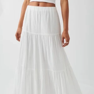 Vit långkjol i bomull - En super snygg långkjol i bomull med resår i midjan. Kjolen är vit och har volanger med rynkade sömmar. Jag är 167 cm och en storlek s täcker mina anklar och de övre delarna av mina fötter✨ inte riktigt min stil längre och därför kommer den inte till användning. Har använt 3-4 gånger. Är dock lite genomskinlig men inget problem med hudfärgade underkläder🥰