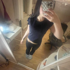 Mörkblå ribbad topp med volangärm - Supersöt mörkblå topp med volangdetaljer på ärmarna. Modellen är ärmlös med en rund halsringning och sitter snyggt figurnära. Perfekt för dig som gillar en enkel men ändå trendig look.