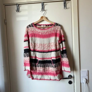 Randig stickad tröja i rosa och svart - Säljer en mysig stickad tröja med breda ränder i rosa, svart och beige. Tröjan har lång ärm, rund halsringning och två fickor framtill. Perfekt för dig som gillar färg och vill ha en chill och unik look. Från märket Odd Molly i storlek 0 som enligt deras storleksguide motsvarar ungefär en Storlek XS men den är stor i storlek. Mer en S/M. Mycket fint skick, jag hittar inga synliga anmärkningar eller defekter. 