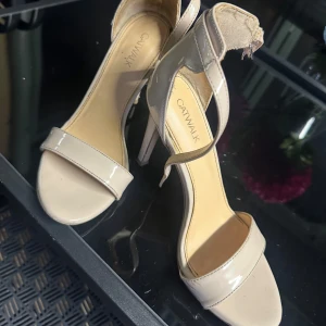 Beige klackade sandaler från Catwalk - Snygga beige sandaler från Catwalk med öppen tå och hög klack. Skorna har en stilren design med rem över tårna och runt vristen. Perfekta för att lyfta din outfit med en elegant touch.